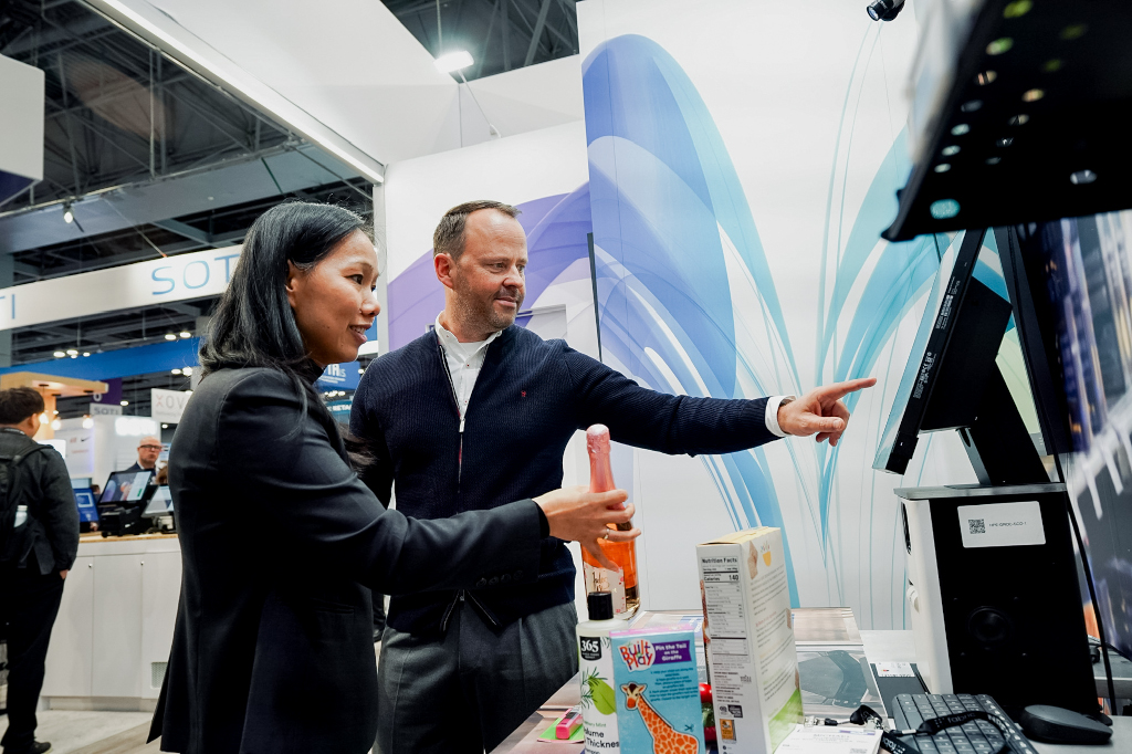 Trinh Le-Fiedler, CEO and Co-Founder of Nomitri, and Michael Scheibner, CEO at GK, mark the integration of Nomitri’s computer vision solutions into GK’s Cloud4Retail platform at NRF 2025. (Photo: GK Software)